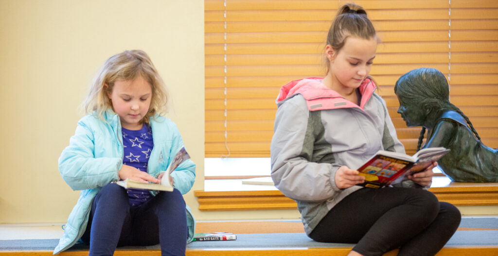 two young girls reading books